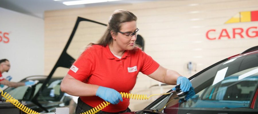 Een vrouwelijke medewerker van Carglass repareert de voorruit van de auto.